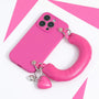 Bright fuchsia phone case with an oversized padded handle and two heart charms, displayed on a pink and white background.