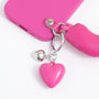 Close-up of a pink heart charm and silver heart charm attached to a fuchsia handle phone case with silver-tone hardware.