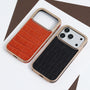 Amber-orange croc-embossed leather phone case with a champagne-gold border, styled on a white and brown geometric background.