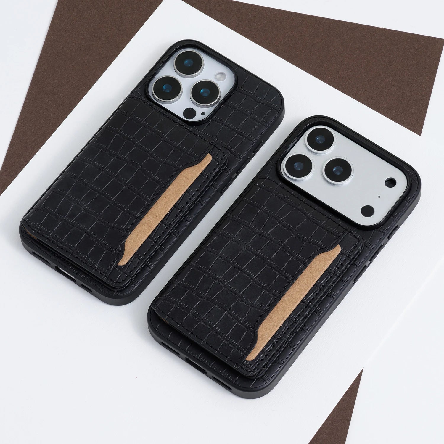 Two crocodile-embossed phone cases with integrated card pockets shown in black, displayed on a white and brown background.