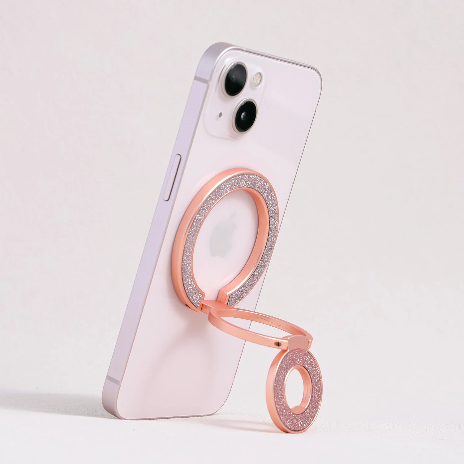 Rose gold MagSafe expandable metal ring stand attached to iPhone, sculptural circular design