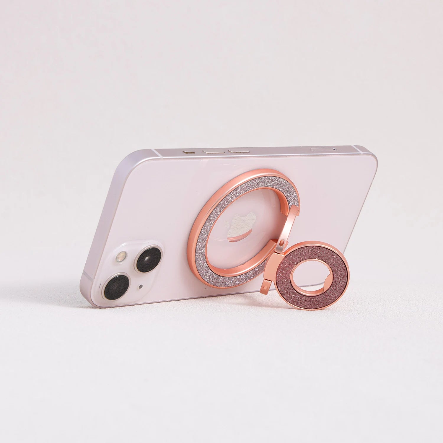 Rose gold MagSafe expandable metal ring stand attached to iPhone, sculptural circular design
