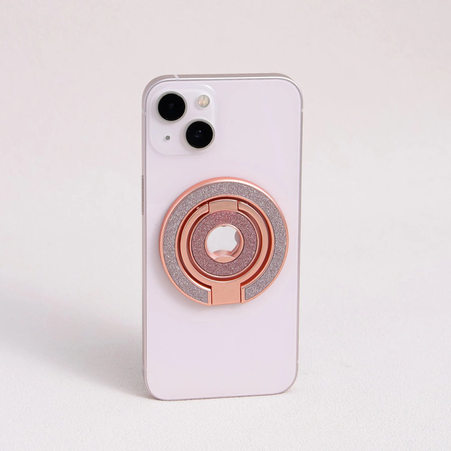 Rose gold MagSafe expandable metal ring stand attached to iPhone, sculptural circular design