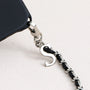 Close-up of polished letter charm on detachable leather-woven phone chain