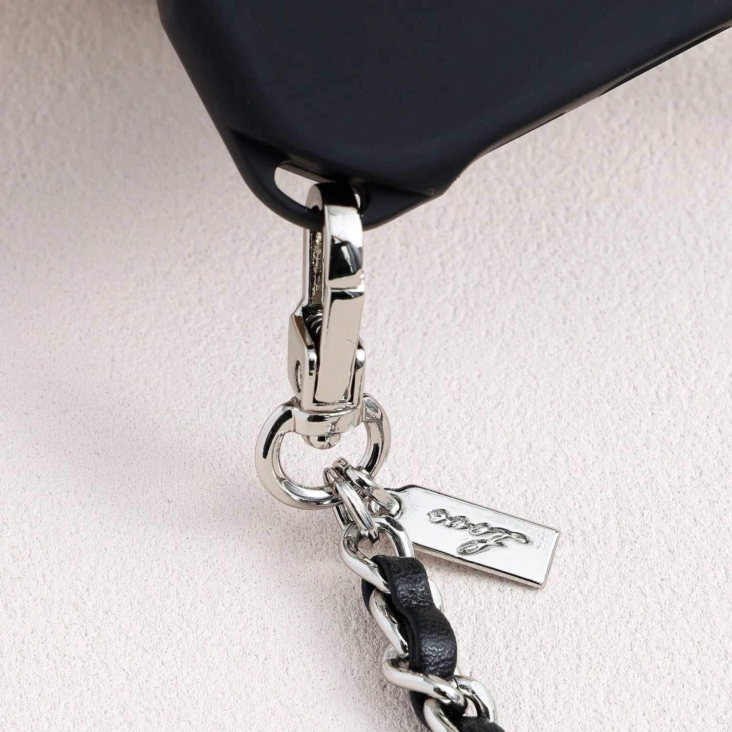 Close-up of metal logo charm and hardware attached to structured TPU phone case