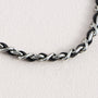 Detail of leather woven through polished metal chain links on detachable phone strap