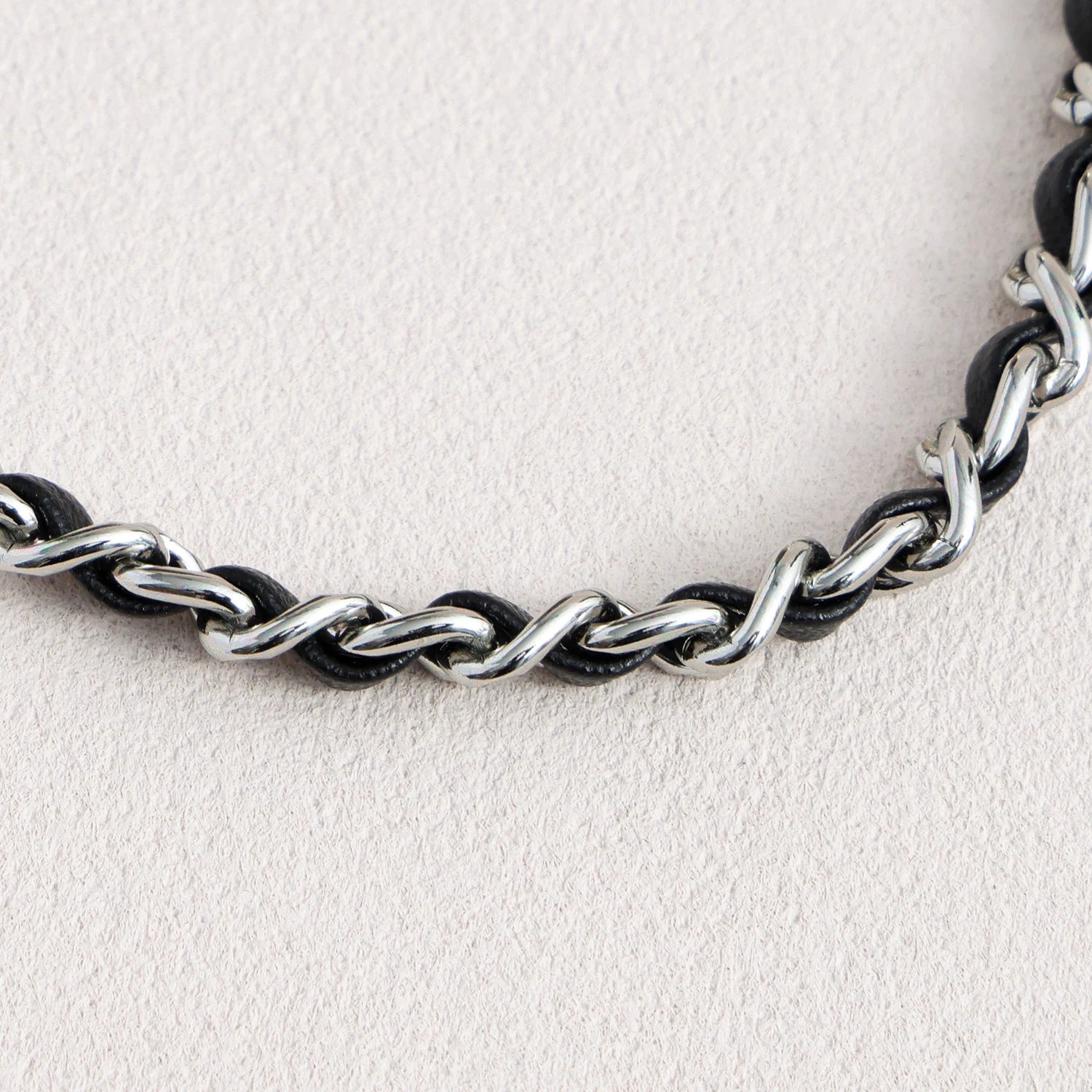 Detail of leather woven through polished metal chain links on detachable phone strap