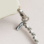 Detail of polished metal logo charm and leather-woven chain on phone case set