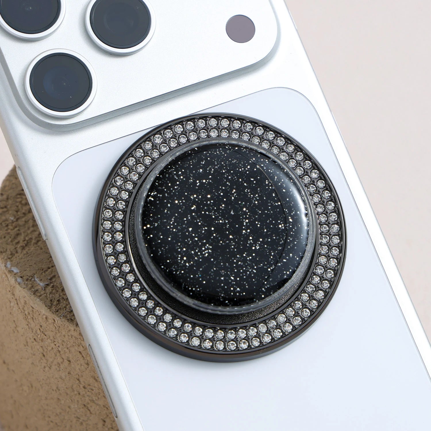 Silver ring phone holder with black glitter center and crystal studded outer ring, offering a sleek airbag-style grip.