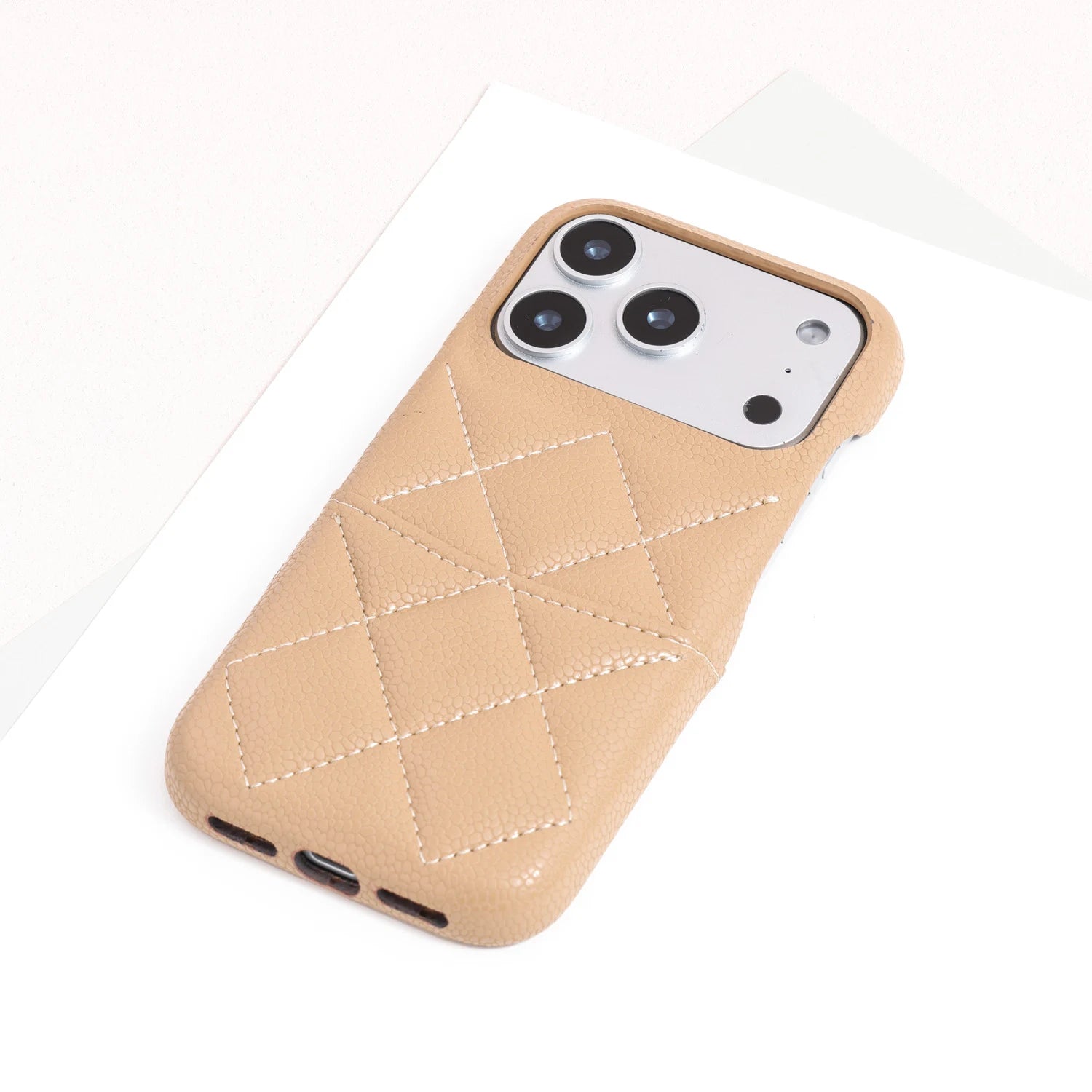 Single sand beige quilted leather phone case with textured finish and structured silhouette.