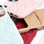 Close-up layered view of pastel and neutral quilted leather phone cases showing grain texture and seam details.