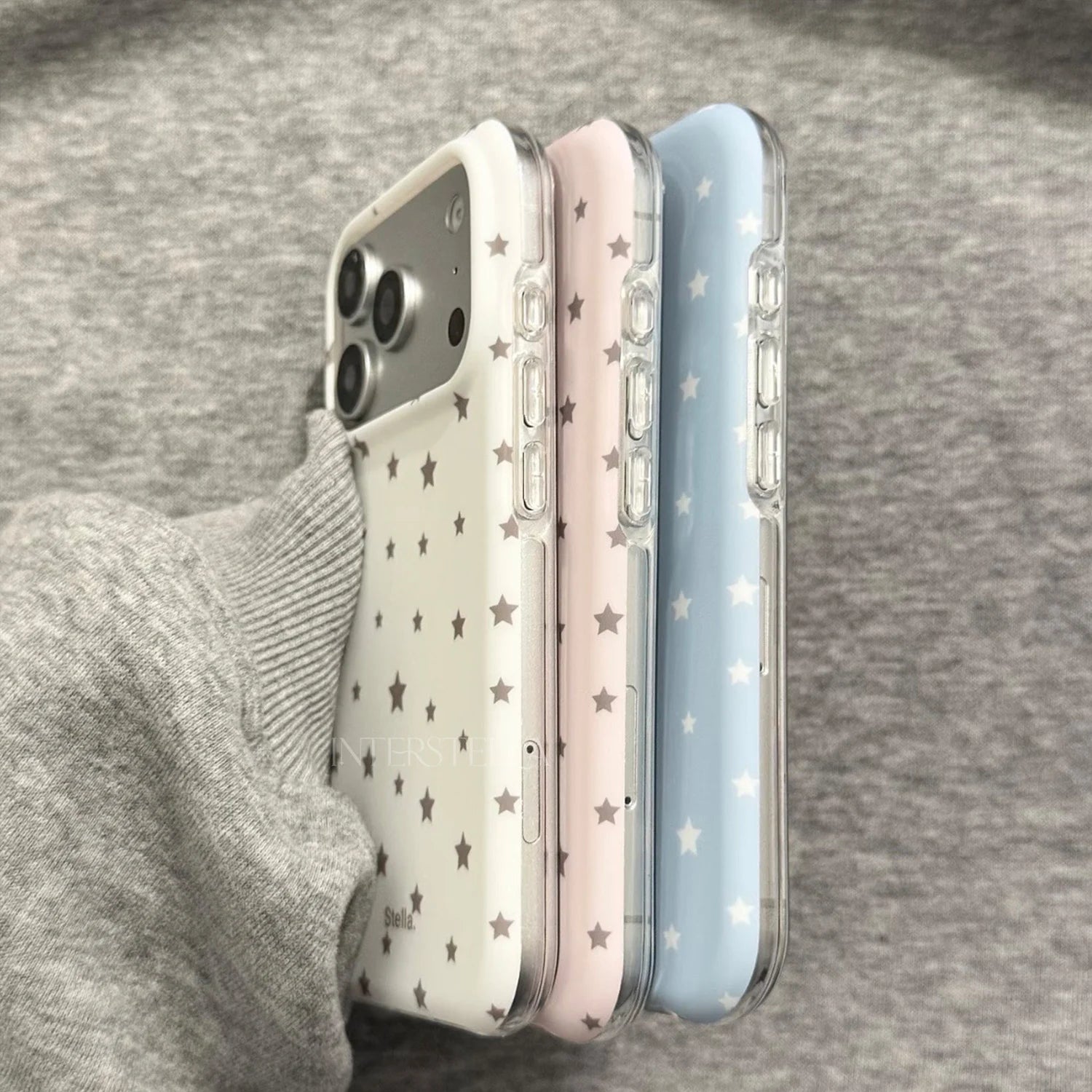 Angled side profile of pastel star phone cases in white, pink, and blue with transparent sides
