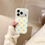 Hand holding a butter yellow phone case with powder blue polka dots and raised camera surround in a soft indoor setting.