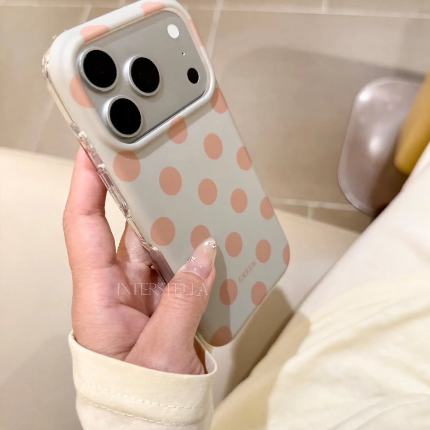 Angled close-up of a soft mint green polka dot phone case with warm beige dots, showing the smooth finish and side profile.