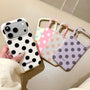 Hand holding the ivory black polka dot phone case with the yellow, pink, mint, and lilac colorways displayed beside it.