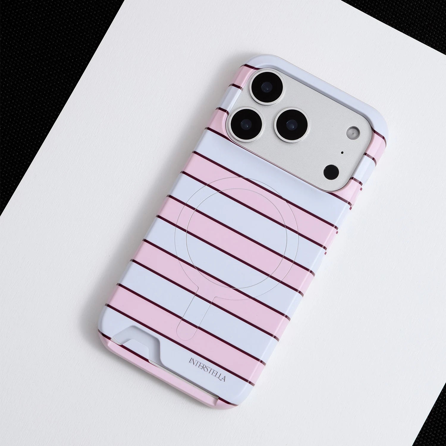 Angled view of Interstella pink striped hard-shell phone case with built-in card slot