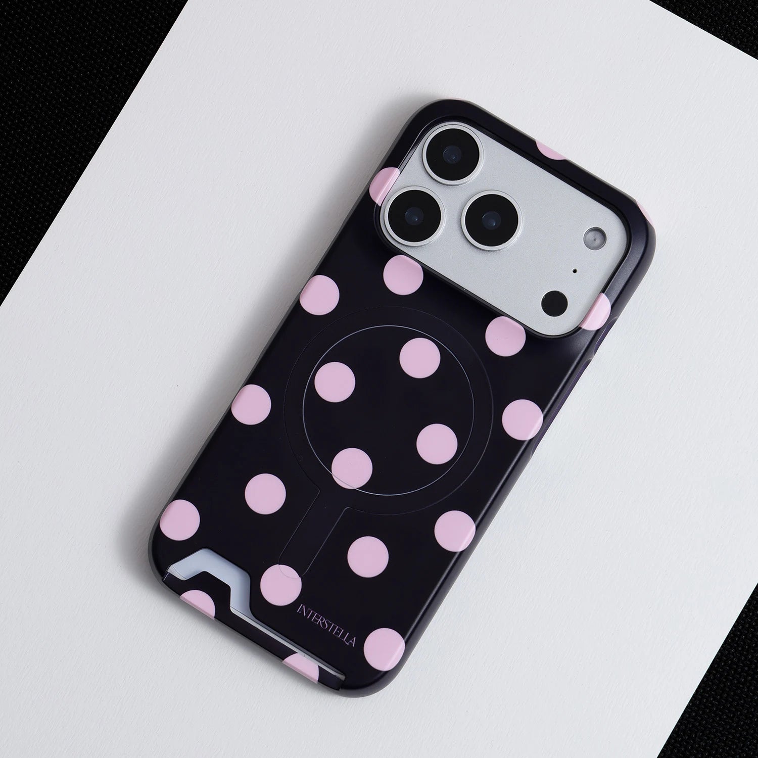 Angled view of Interstella polka dot hard-shell phone case with built-in card slot