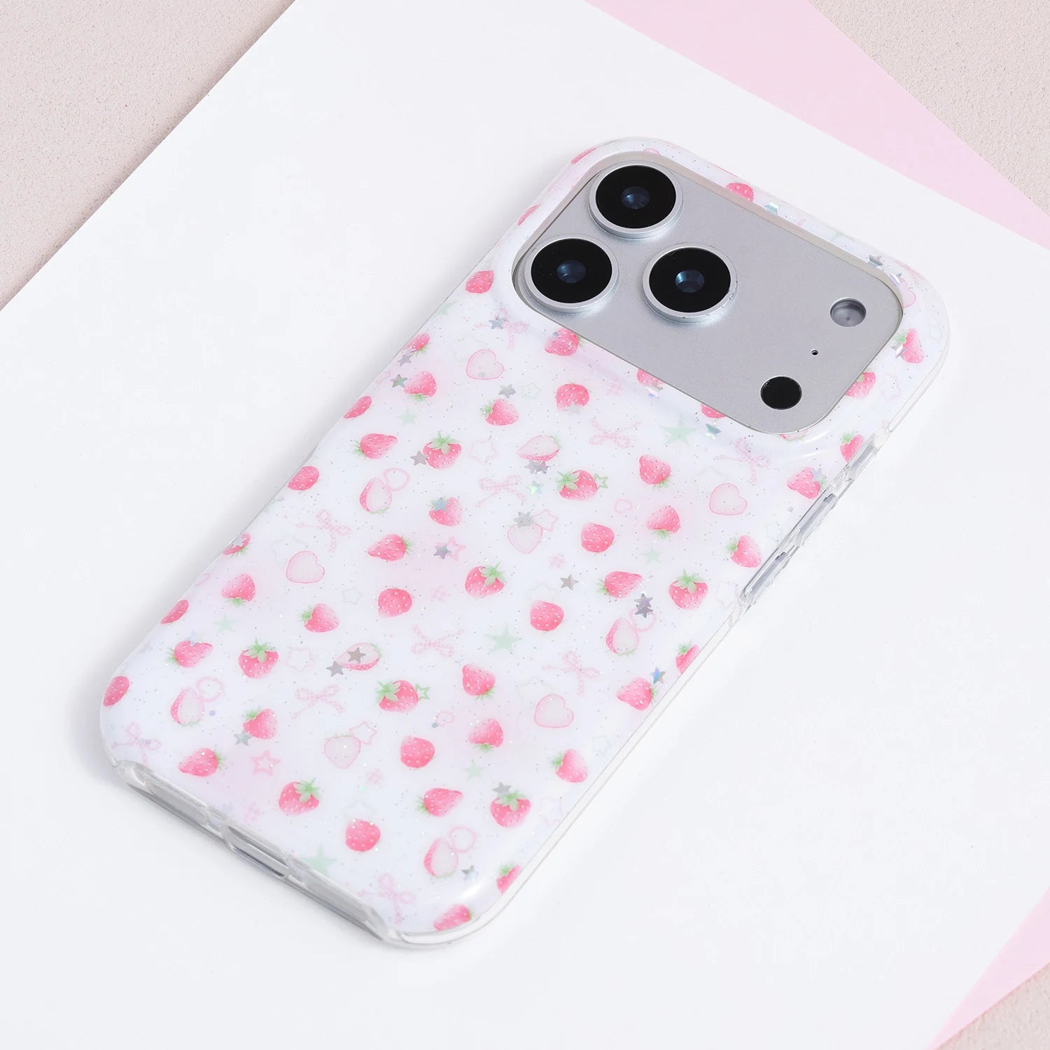 Full view of a white TPU phone case with tiny strawberries, pastel bows, hearts, stars, and soft confetti-like detailing.