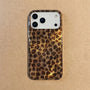 Hand holding a glossy petite leopard phone case in warm honey-brown tones with a refined small-scale animal pattern and raised camera surround.
