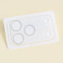 Clear acrylic camera lens protector with silver glitter rings around three camera lens openings, displayed on a pale background.