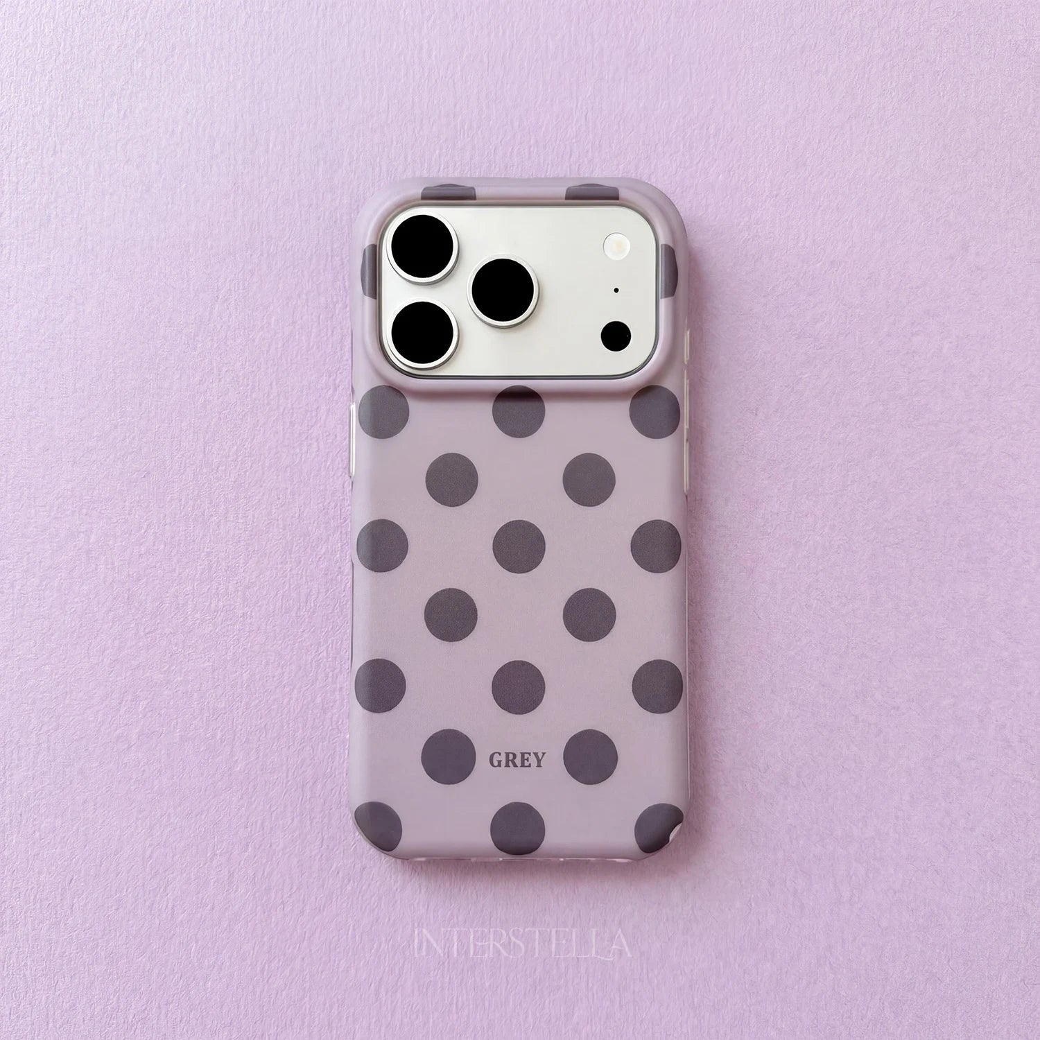 Lilac polka dot phone case with charcoal grey dots and raised camera surround on a soft lavender background.