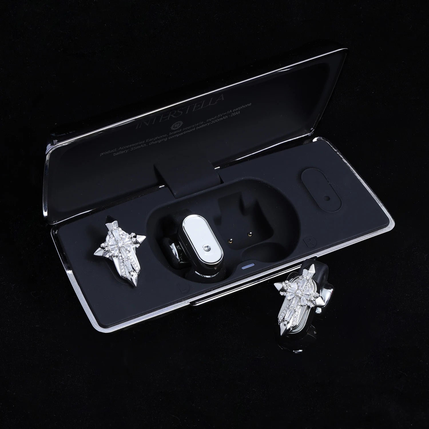 Silver-tone crystal cross ear charms displayed with black Interstella magnetic earphone charging case