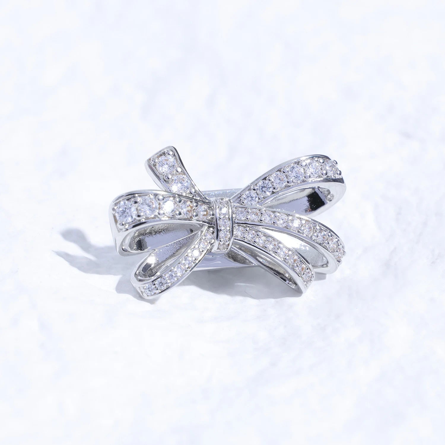 Crystal butterfly ribbon ear charm with Swarovski detailing and silver-tone finish on a white textured surface