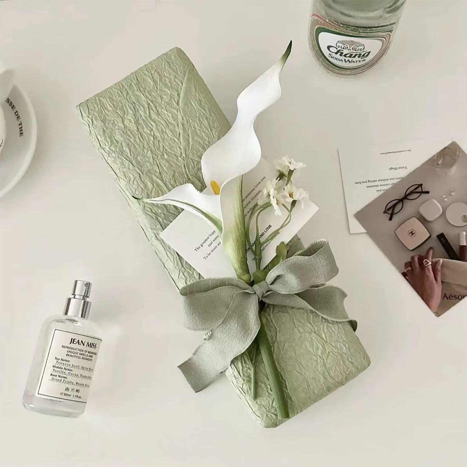 Gift box with white flowers and green ribbon on a light surface