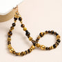 Tiger’s eye gemstone phone strap with gold metal accents, detachable bracelet design