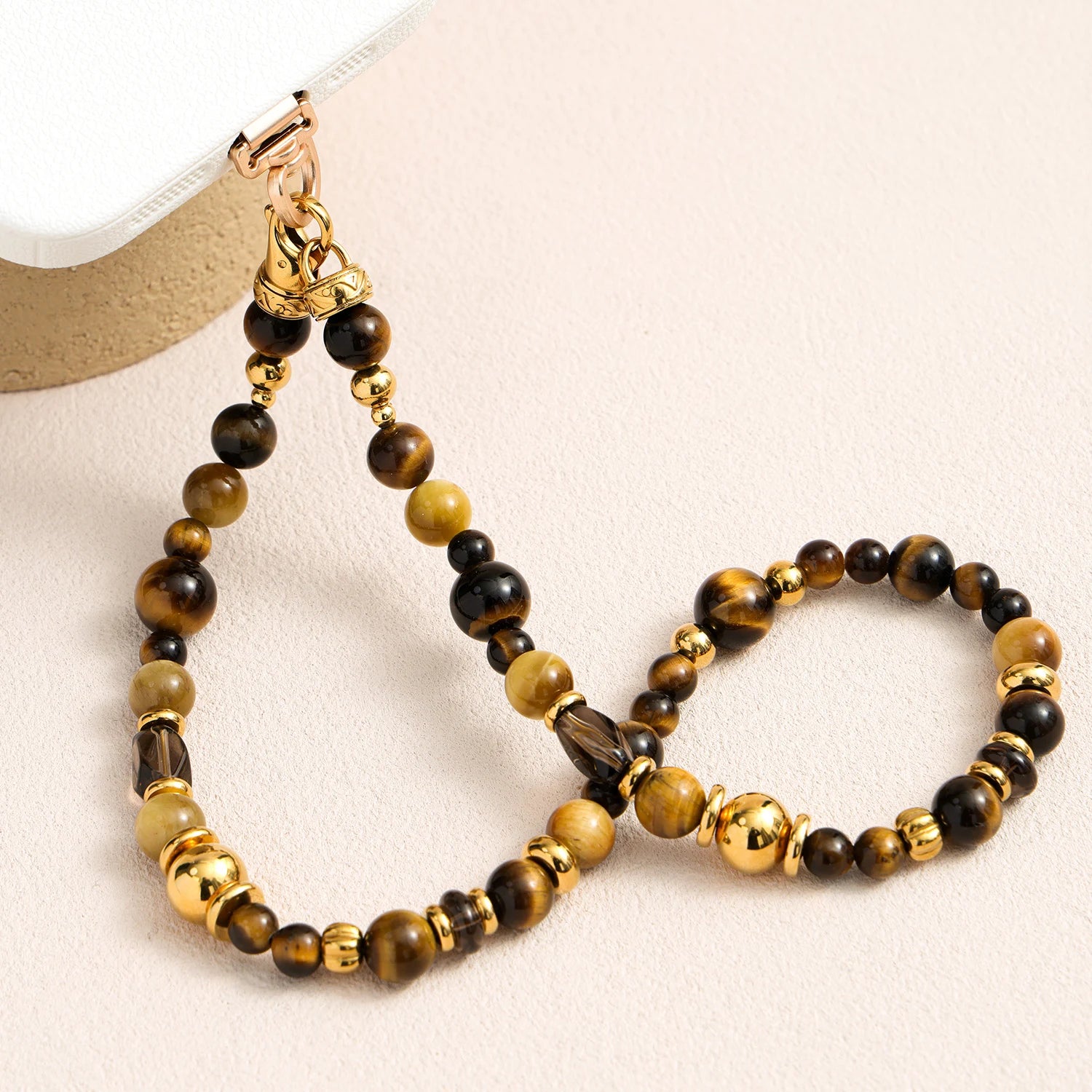 Tiger’s eye gemstone phone strap with gold metal accents, detachable bracelet design