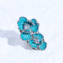 Single turquoise floral magnetic ear charm with silver-tone edges and crystal centers displayed against a soft white background.