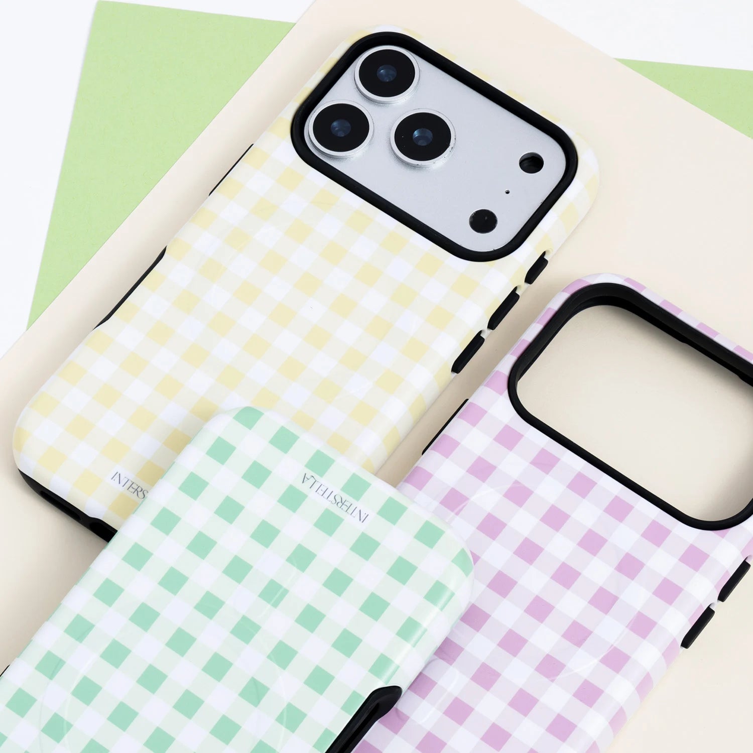 Three pastel gingham phone cases in Mint, Blush, and Buttercream, shown together with a dual-layer hard shell and silicone construction and black camera surround.
