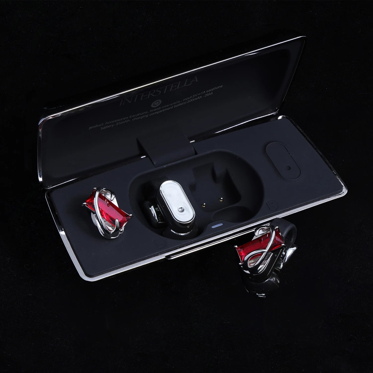Red gemstone ear charms displayed with black Interstella magnetic earphone charging case