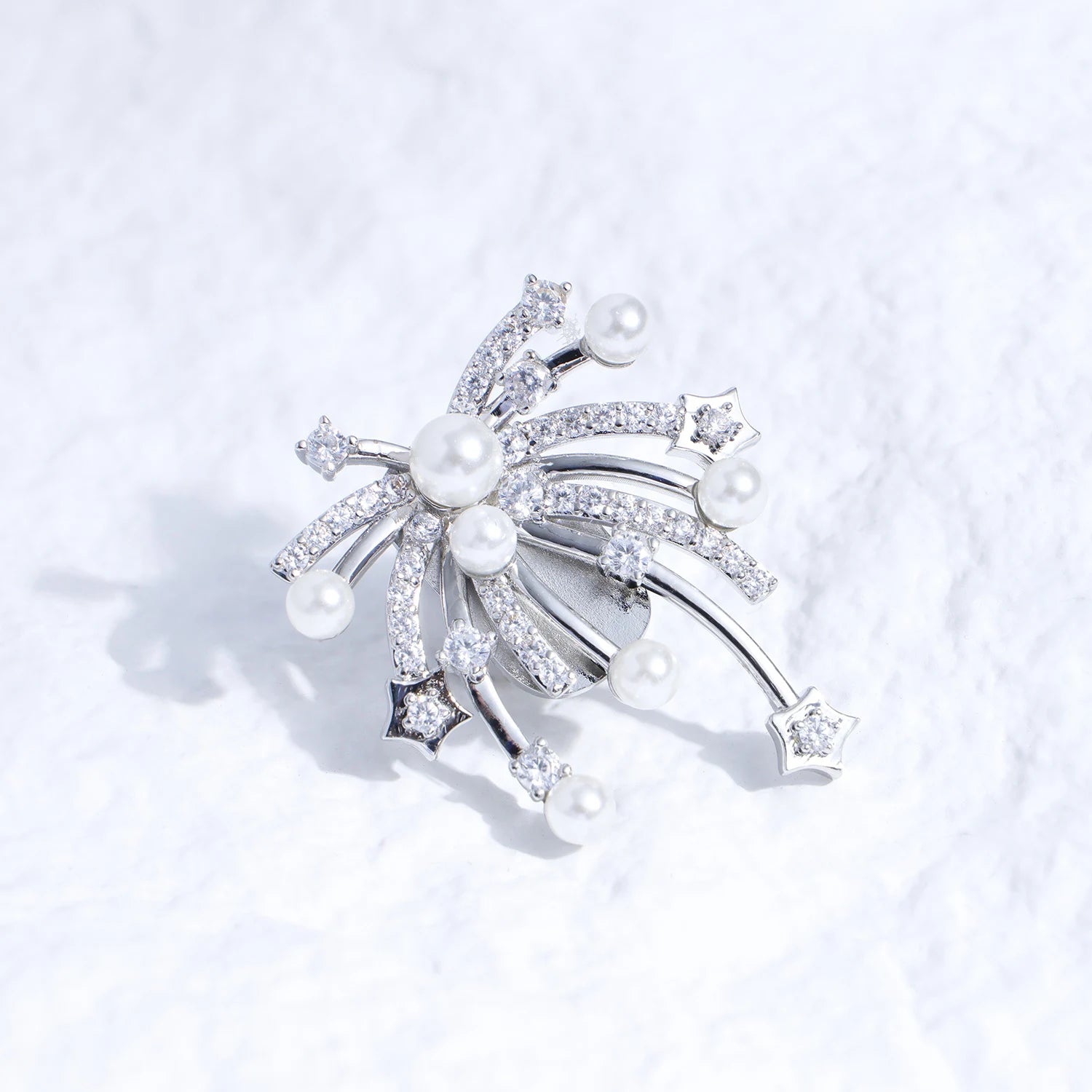 Pearl and crystal starfall ear charm with silver-tone plated finish on a white textured surface