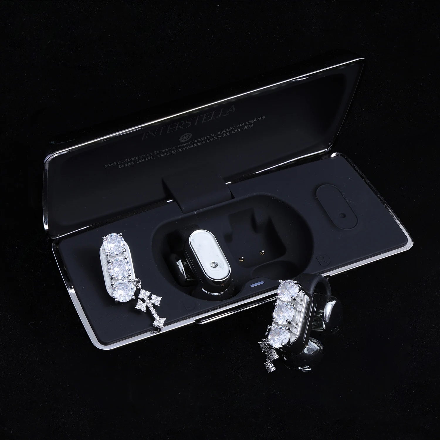 Crystal ear charms with cross detail displayed with black Interstella magnetic earphone charging case