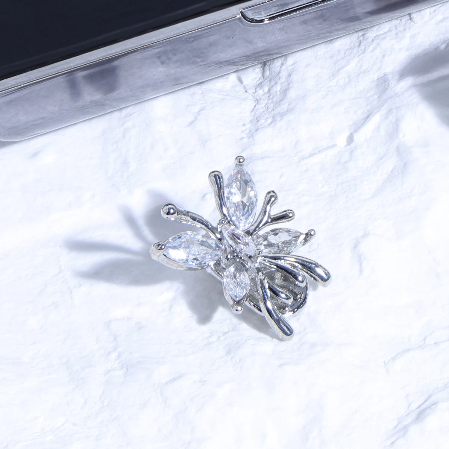 Silver crystal butterfly ear charm with multi-cut stones on textured white background