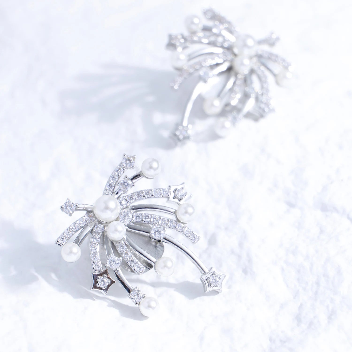 Pearl and crystal starfall ear charm with silver-tone plated finish on a white textured surface