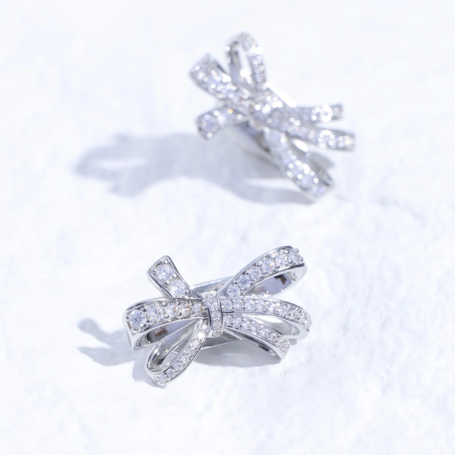 Crystal butterfly ribbon ear charm with Swarovski detailing and silver-tone finish on a white textured surface