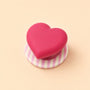 Rose pink heart phone grip stand with a pink-and-white striped round base displayed on a soft beige background.
