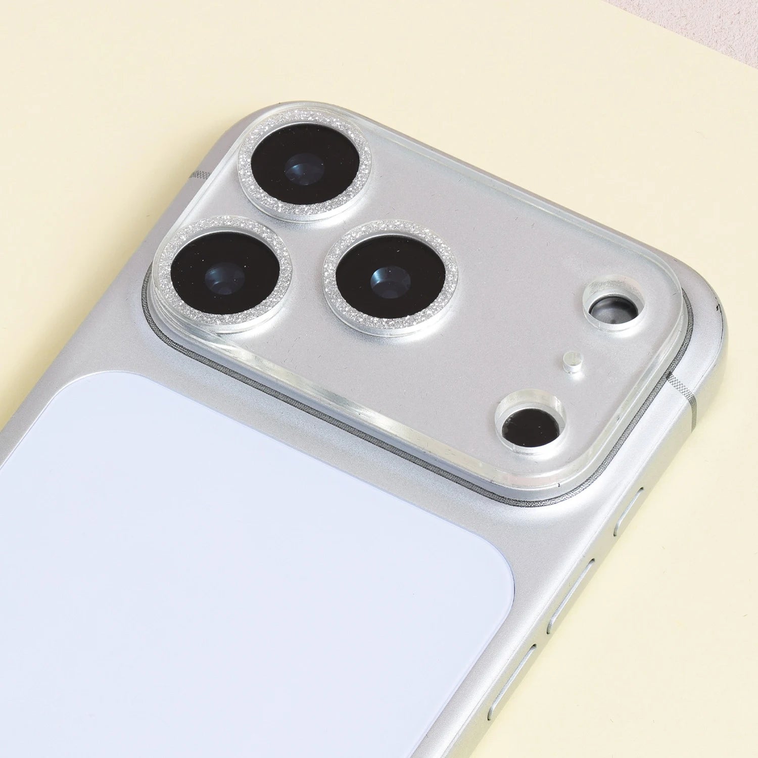 Silver halo acrylic camera lens protector installed on a silver iPhone, highlighting glitter ring borders around each camera lens.