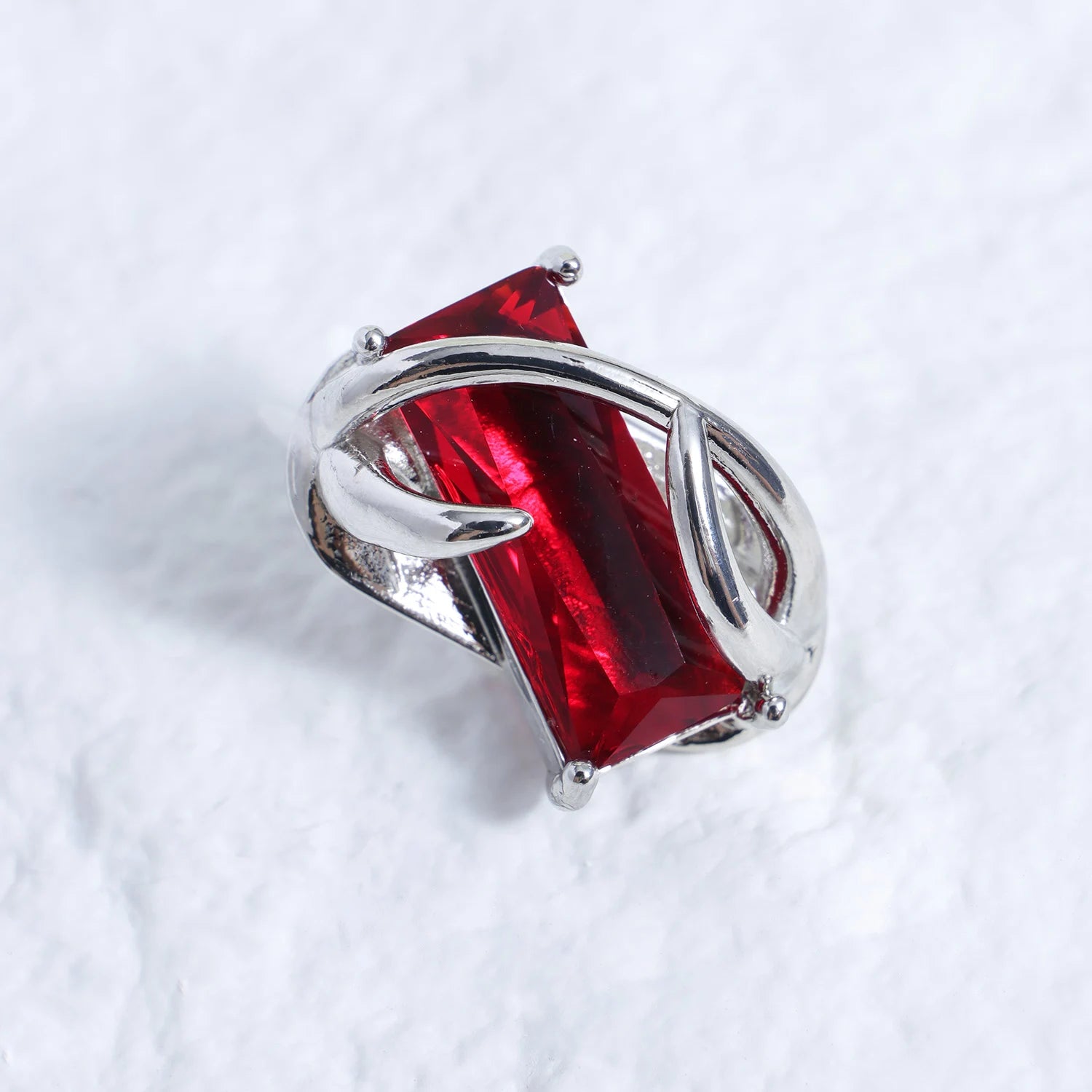 Silver-tone ear charm with rectangular red gemstone on a white textured background