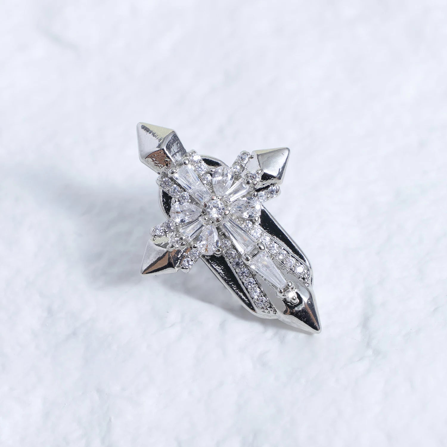 Silver-tone crystal cross ear charm with clear faceted stones on a white textured background