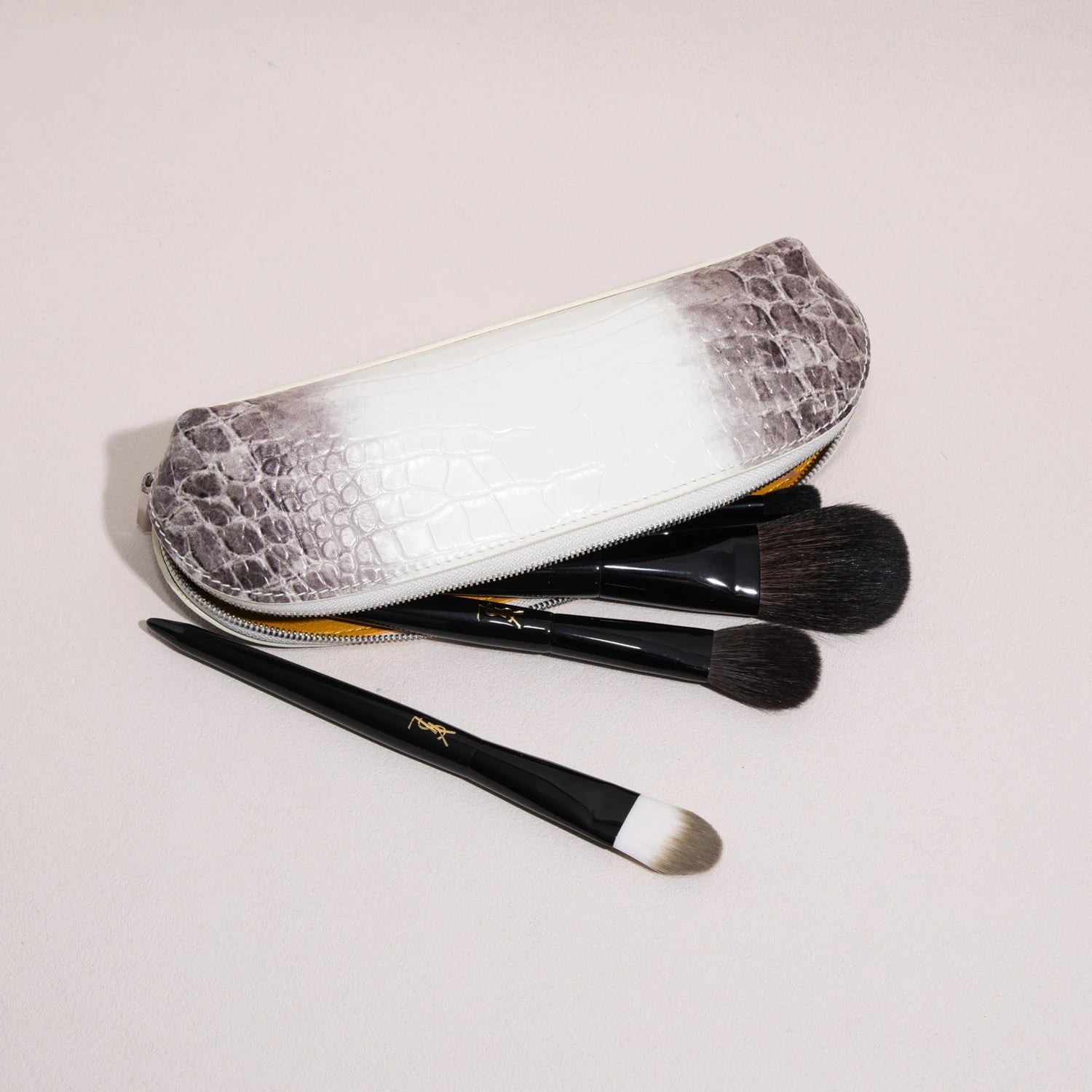 Open rectangular brow pencil pouch holding makeup brushes inside a structured leather case