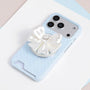 Ivory white jewel bow phone grip stand attached to a pale blue micro polka dot phone case.