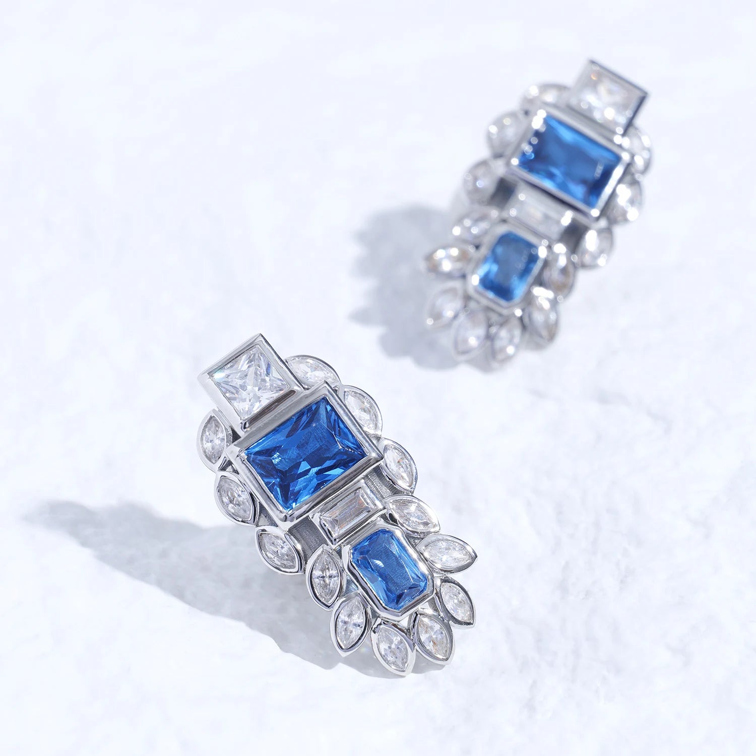 Blue gemstone ear charm with Swarovski crystal accents and silver-tone plated reliquary silhouette on a white textured surface