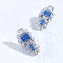 Blue gemstone ear charm with Swarovski crystal accents and silver-tone plated reliquary silhouette on a white textured surface