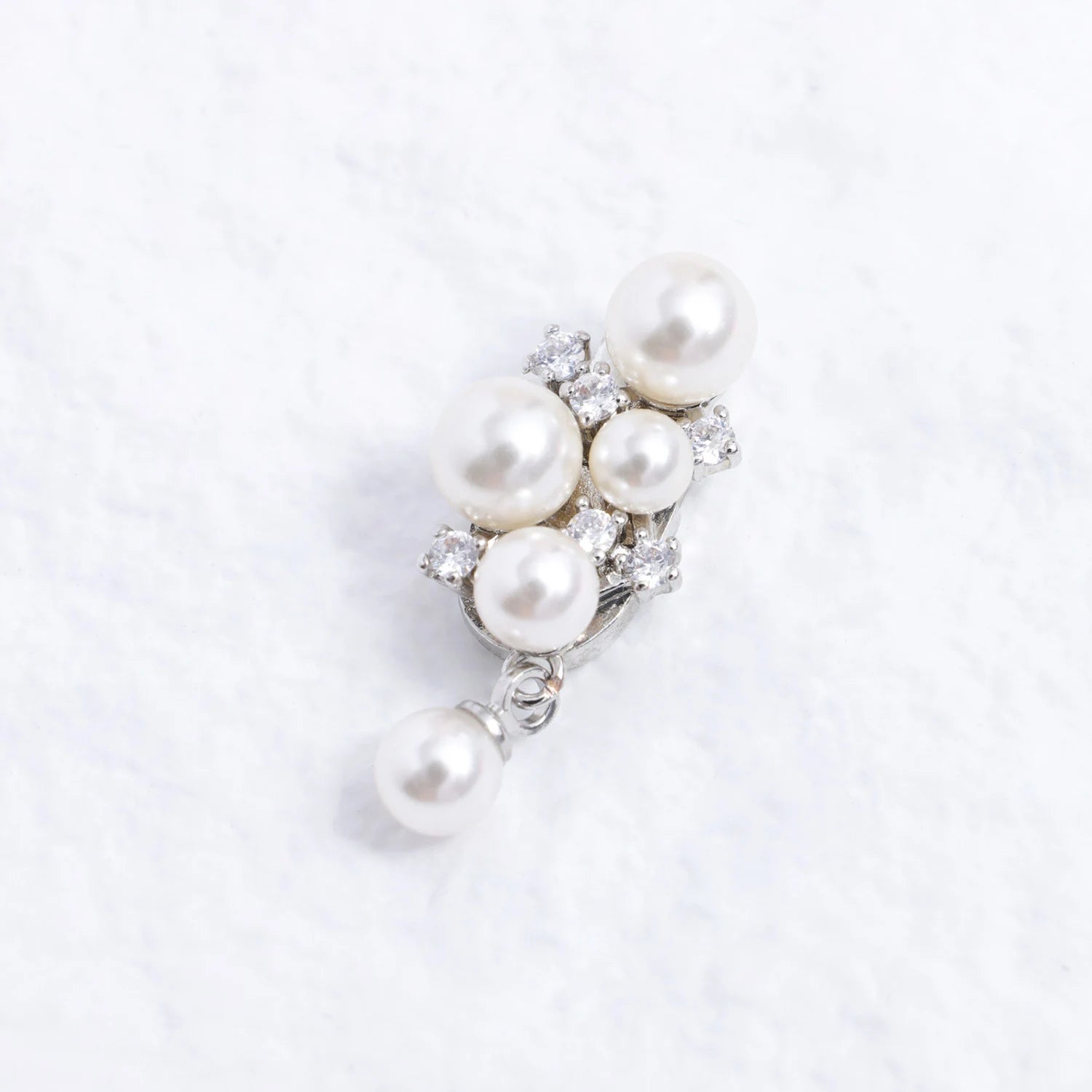 Close-up of a pearl and Swarovski crystal ear charm with starfall silhouette, silver-tone plated finish, and delicate drop pearl detail.
