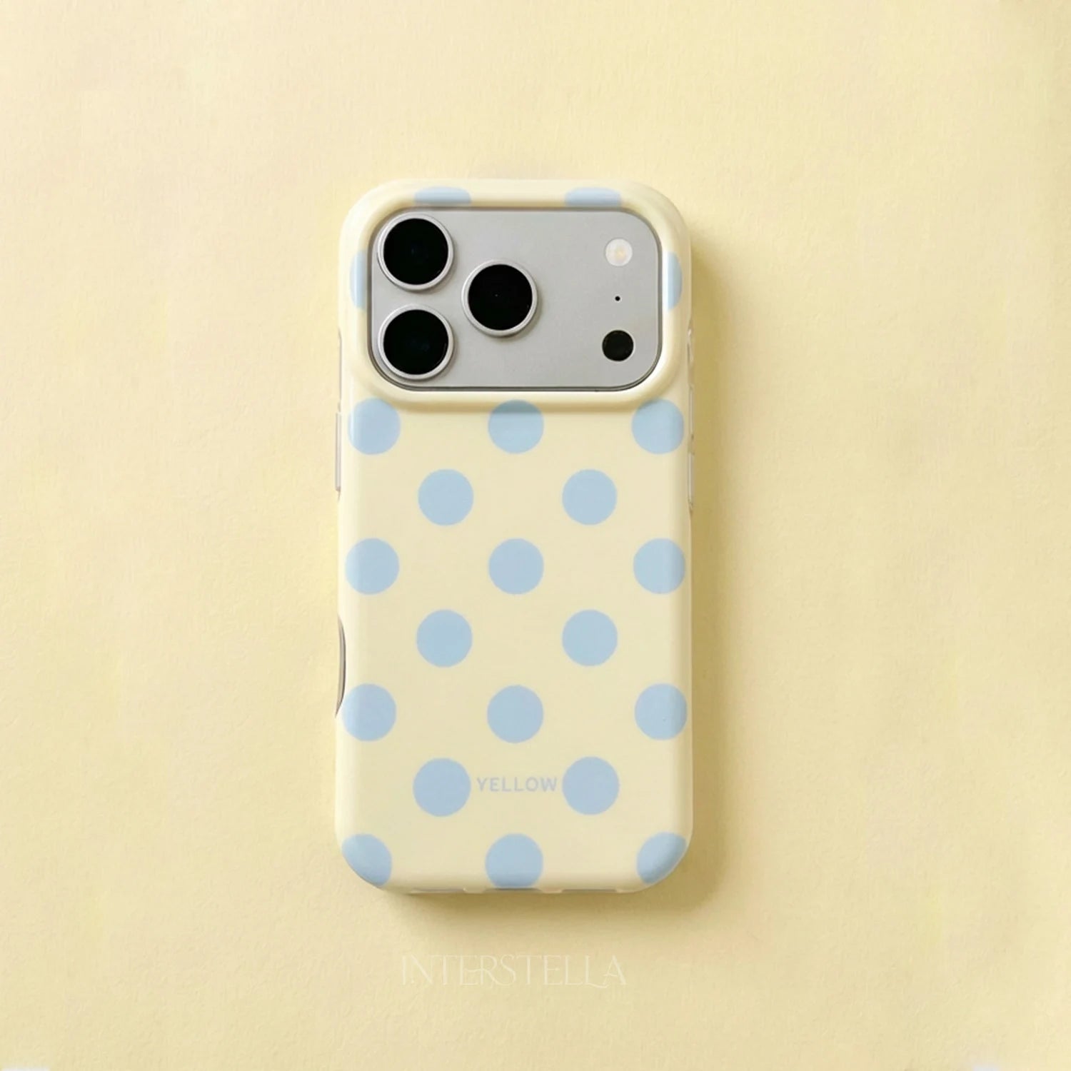 Butter yellow polka dot phone case with powder blue dots and raised camera surround on a pale yellow background.