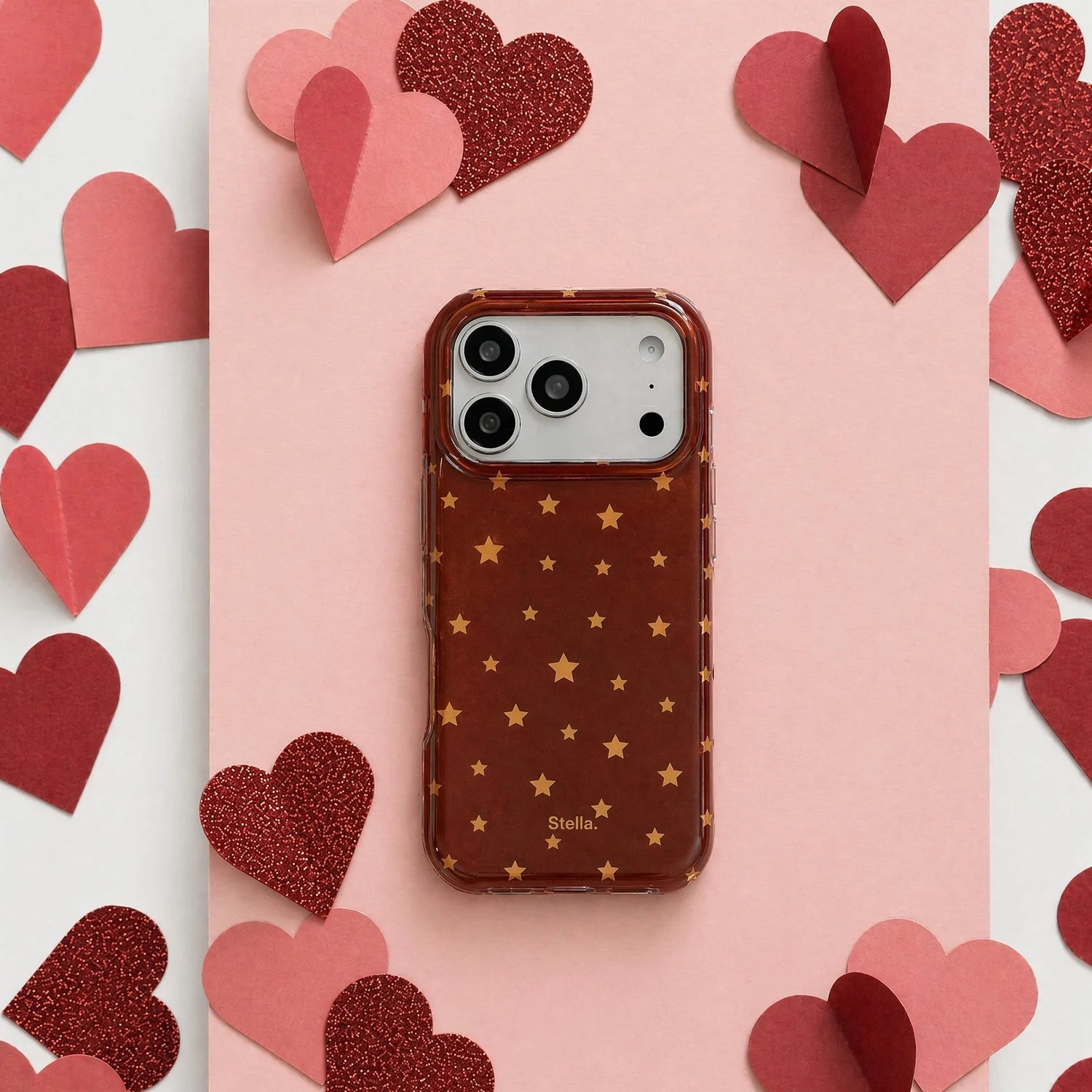 Deep red shimmering star phone case with gold stars on a pink heart-themed background