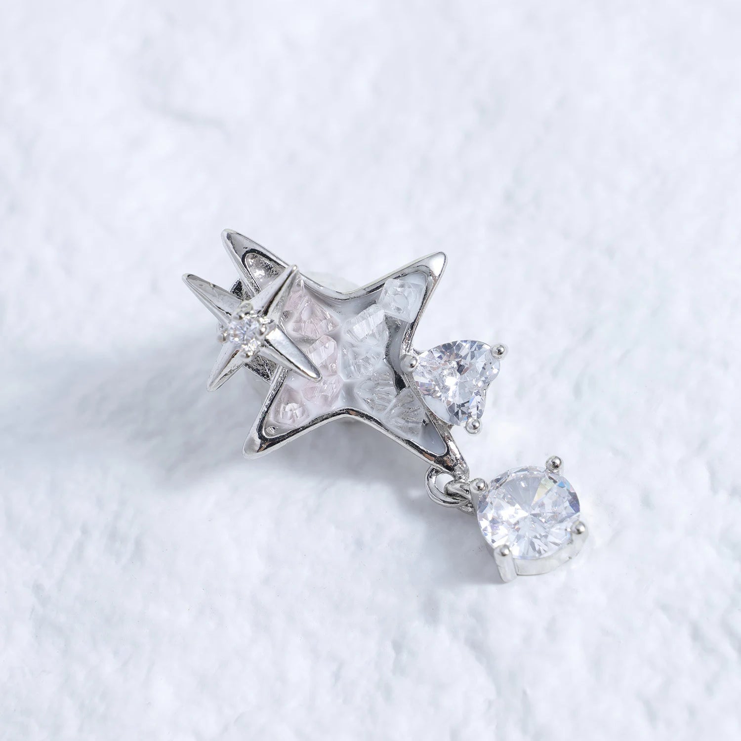 Silver-tone star ear charm with clear crystal drop on a white textured background